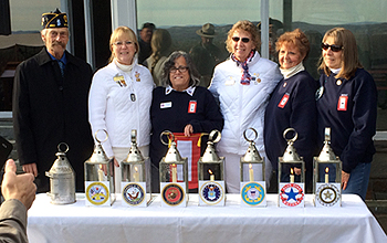 The Gold Star and Blue Star mothers along with an American Legion member standing with the lighted lanterns