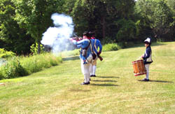 Members of the Saratoga National Historical Park staff and volunteers in Colonial soldier's uniform perform a musket firing demonstration.